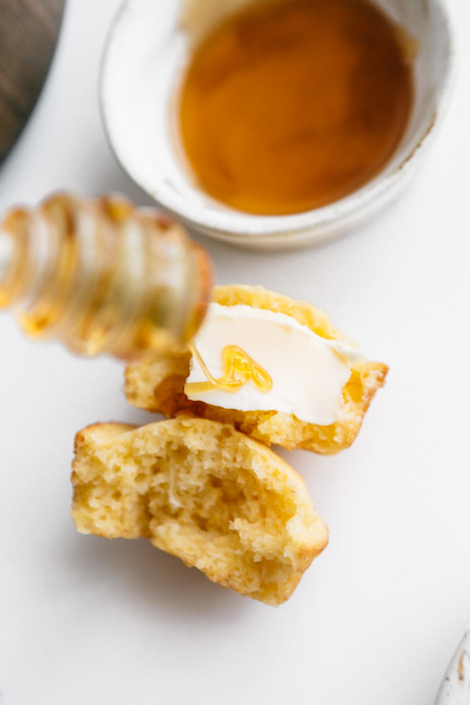 Drizzling honey onto a cornbread muffin 