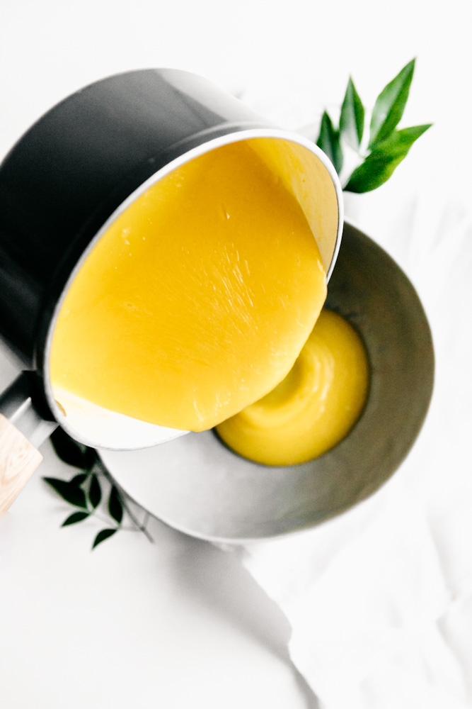 Pouring fresh lemon curd from a pan into a bowl. 