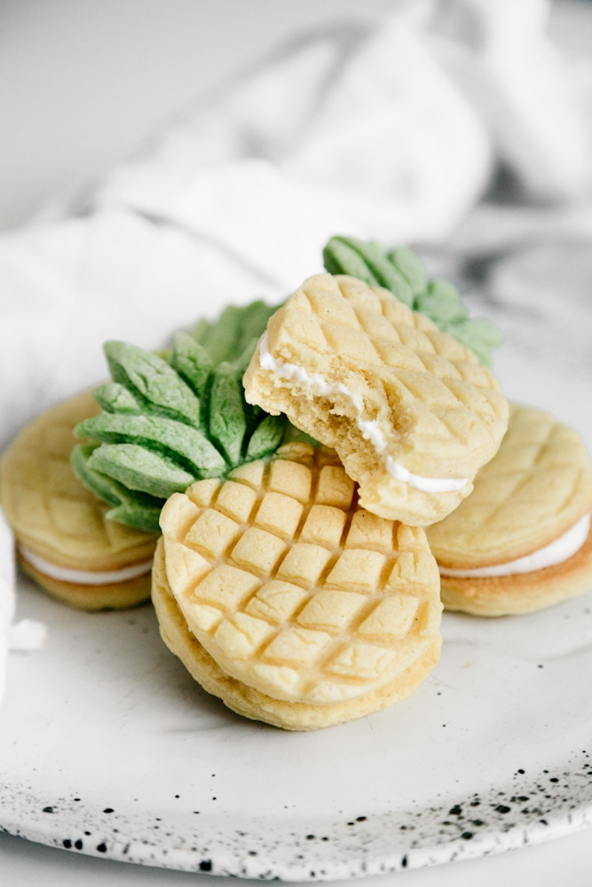 A bite out of a pineapple sandwich cookie. 