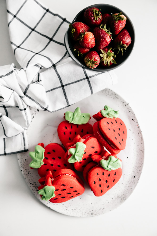 Strawberries and a plate of sandwich cookies. 
