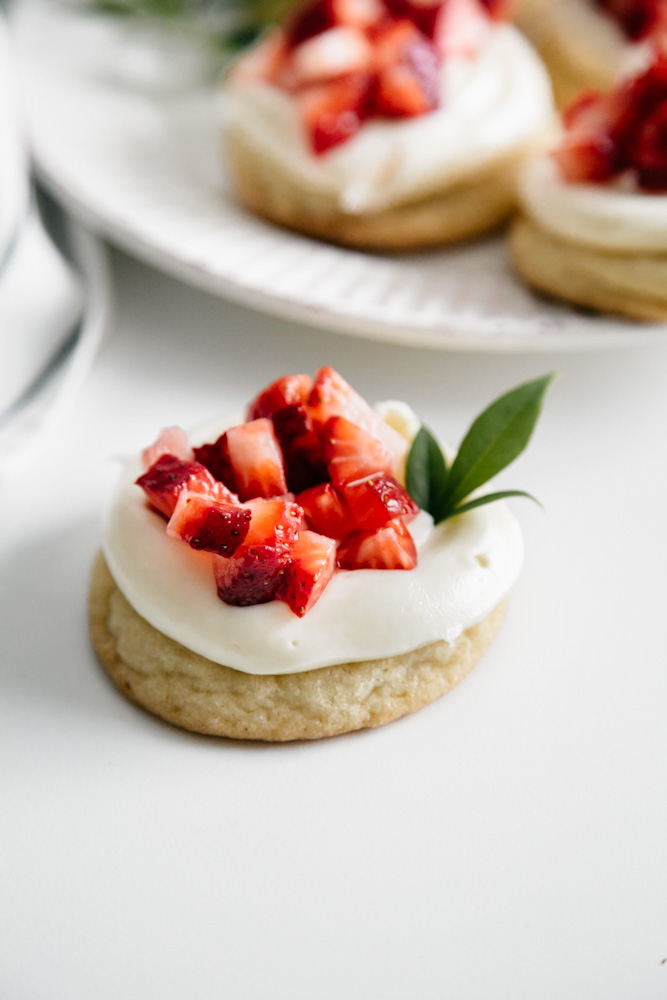 A cookie with frosting and strawberries. 