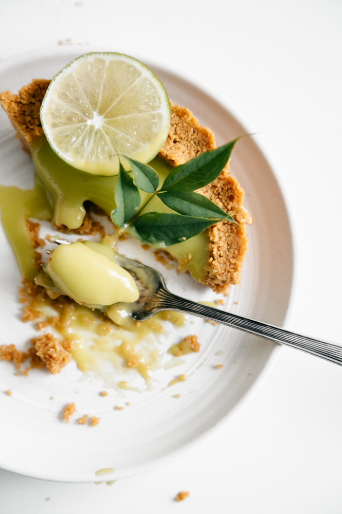 A slice of deep-dish lime curd tart partially eaten. 