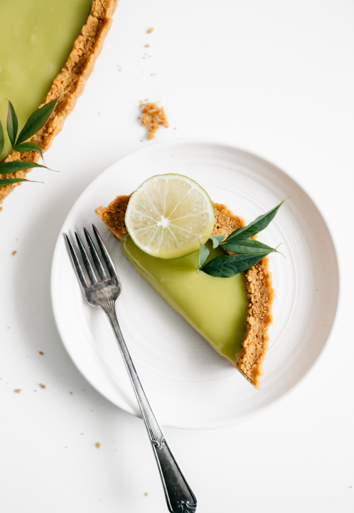 A rounded slice of a deep-dish lime curd tart. 