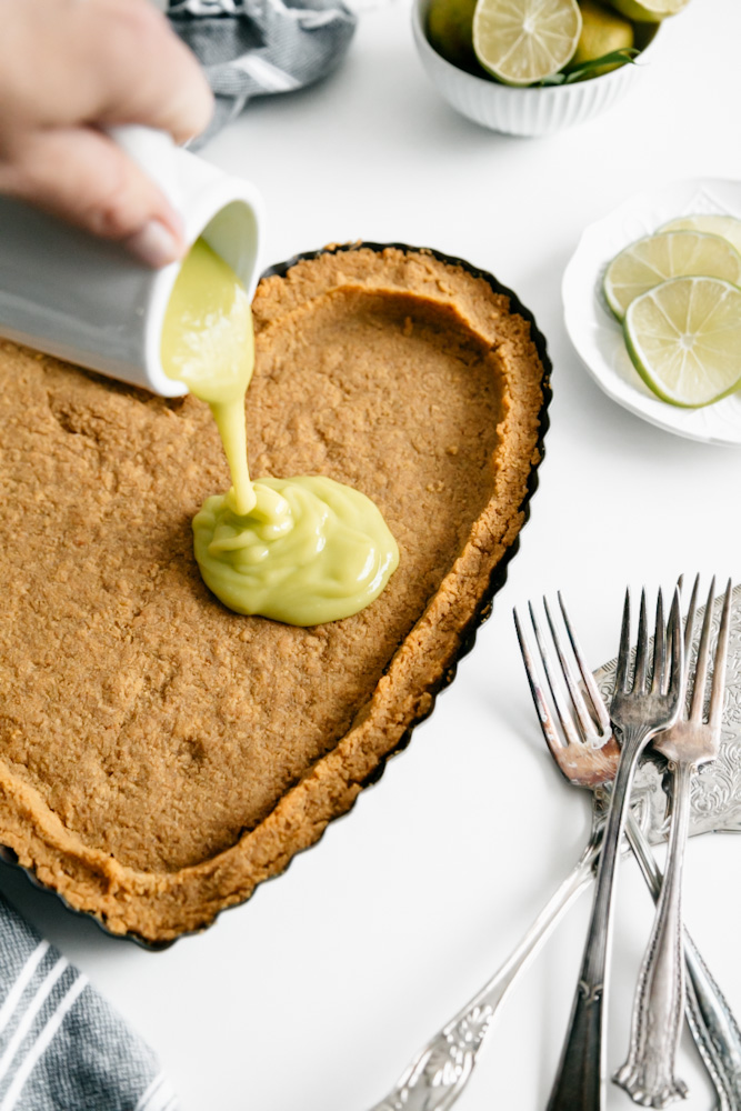 Pouring lime curd into a heart shaped graham cracker crust. 