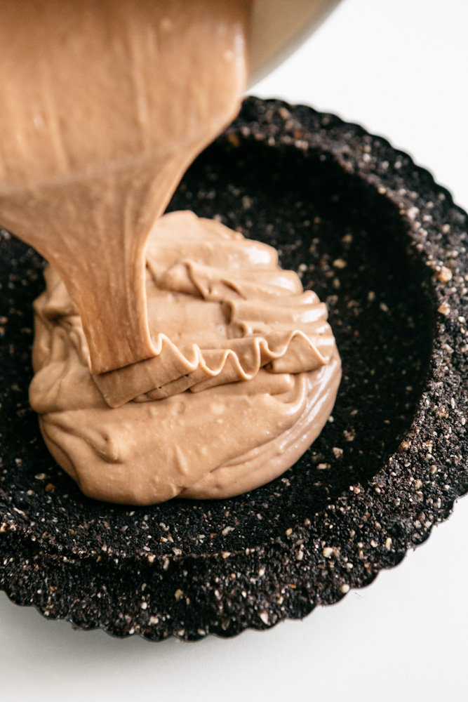 Nutella cheesecake batter being poured into crust 