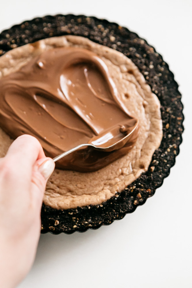 Spreading Nutella on a cheesecake tart 