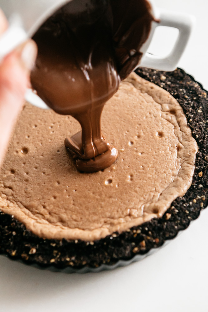 Pouring nutella onto a cheesecake tart 