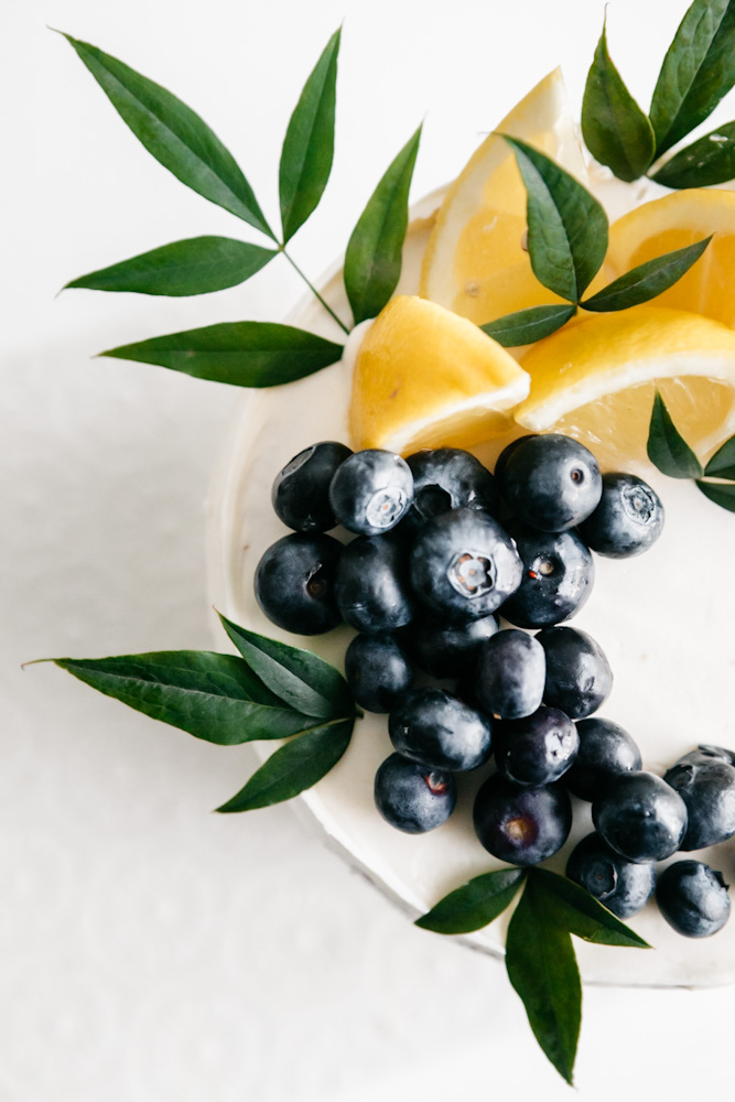 Closeup shot of blueberries and lemon wedges atop a cake 