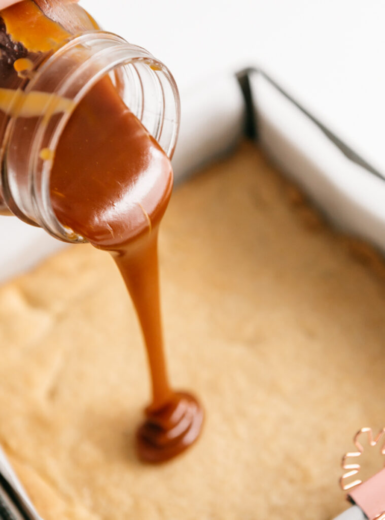 Pouring caramel from a jar onto shortbread 
