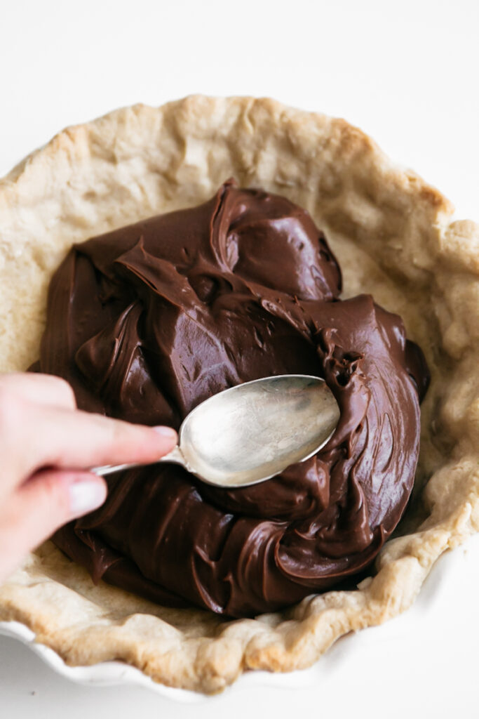 Spooning chocolate filling into a pie crust 