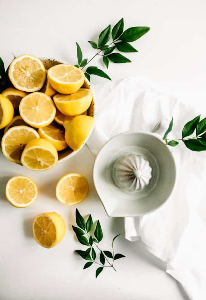 Lemons on a white table with a juicer 