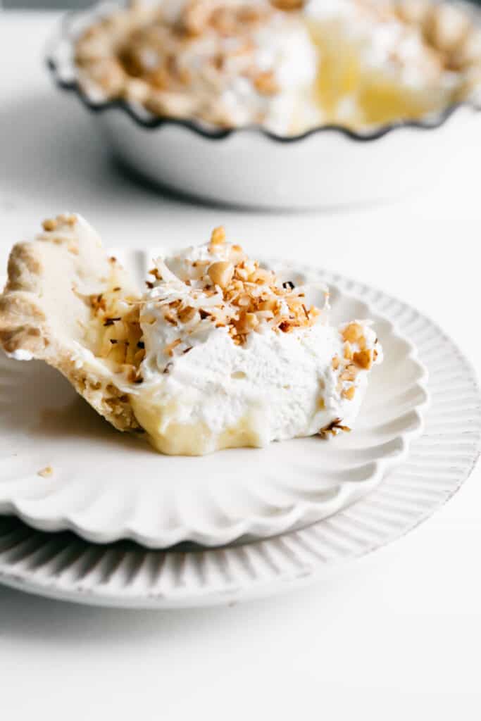 A slice of Coconut Cream Pie on a white plate 