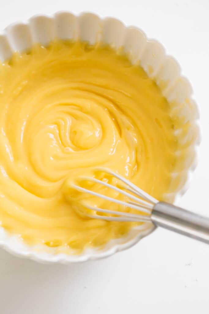 A bowl of lemon curd with a whisk in it