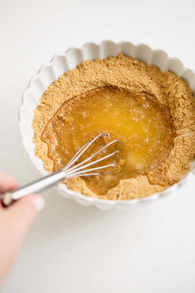 Graham cracker crumbs and melted butter in a bowl 