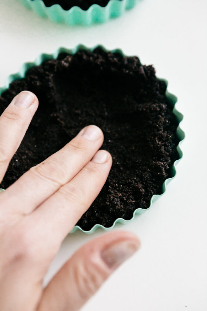 Pressing an oreo crust into a tart pan 