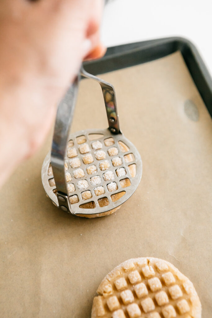 Pressing a cookie with a potato masher 