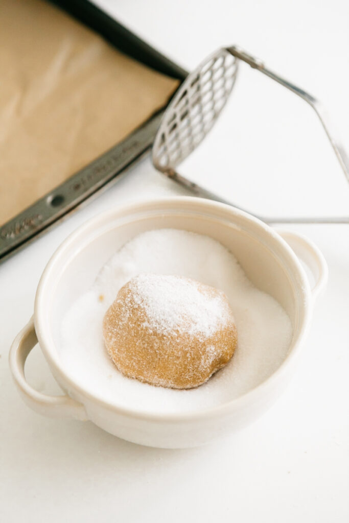 Peanut butter cookie dough in a bowl of granulated sugar 