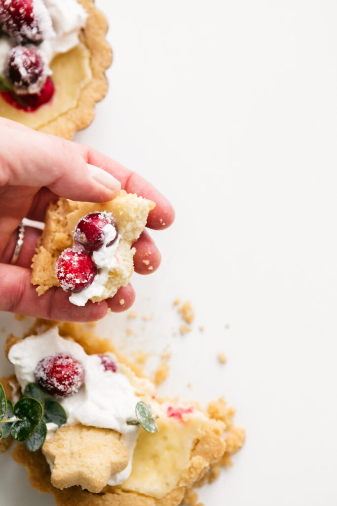 Holding a piece of the Mini Cranberry Cheesecake Tarts