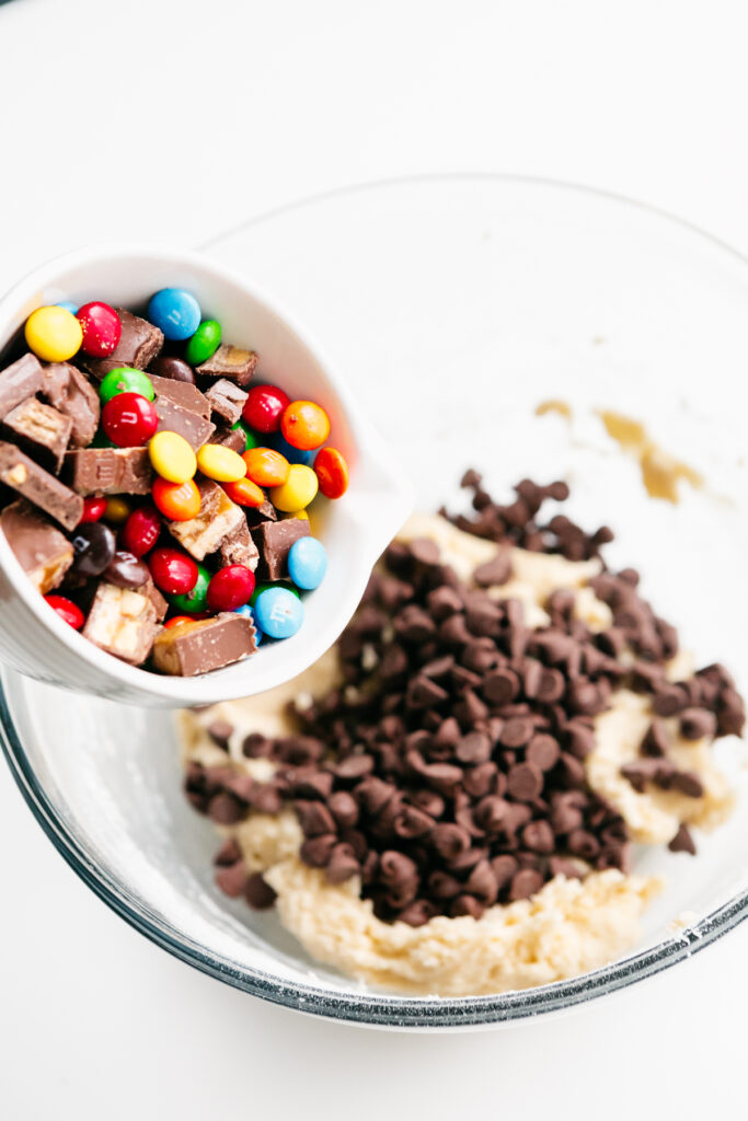 Pouring candy into a cookie dough bowl 