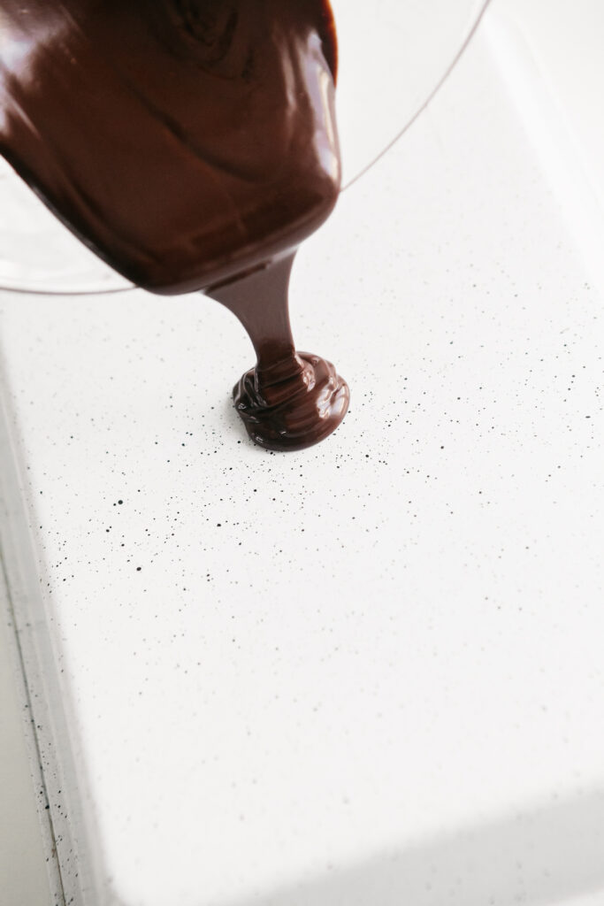 Pouring melted chocolate onto a tray 