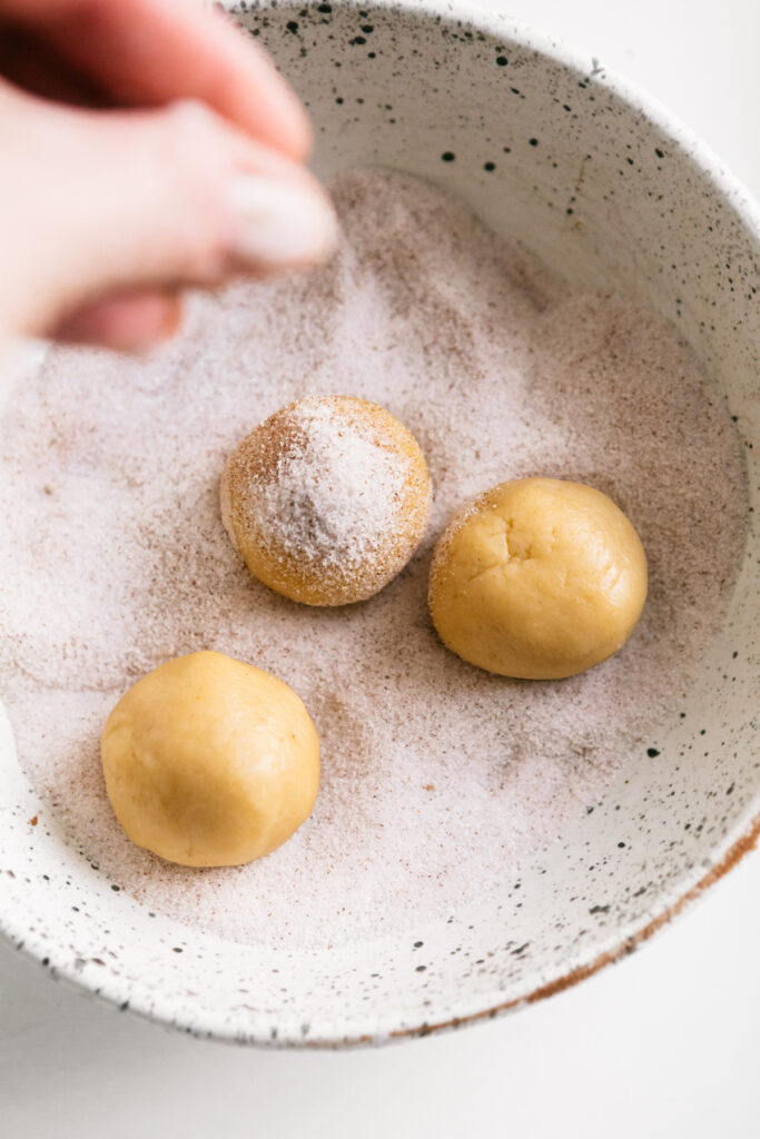 Sprinkling cinnamon and sugar on cookie dough balls 