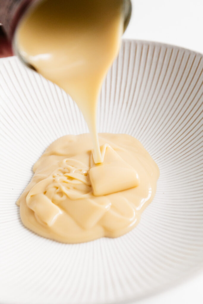 Sweetened condensed milk being poured into a bowl 