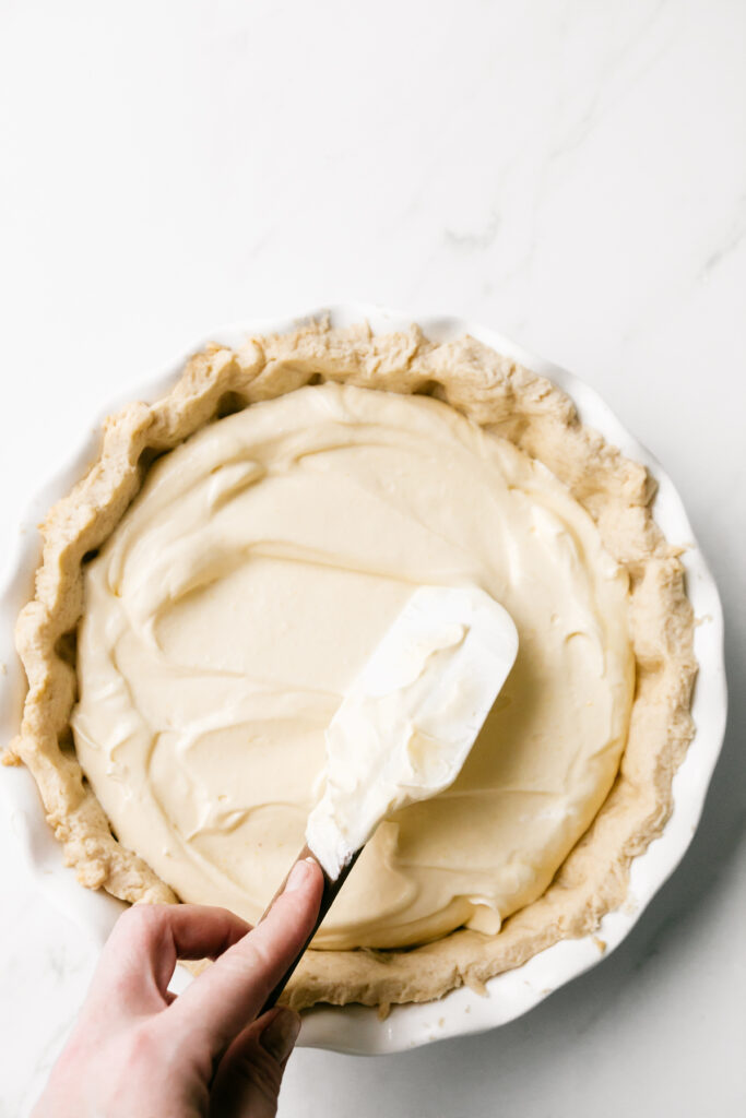 Smoothing lemon pie filling into a crust 