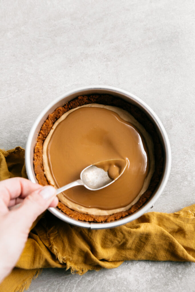 Smoothing cookie butter on a cheesecake. 