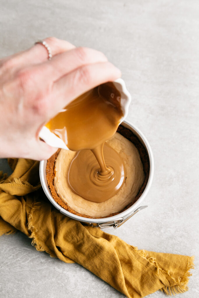 Pouring cookie butter over a cheesecake. 