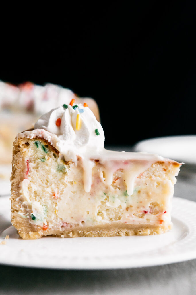 A slice of Funfetti Birthday Cheesecake on a white plate 