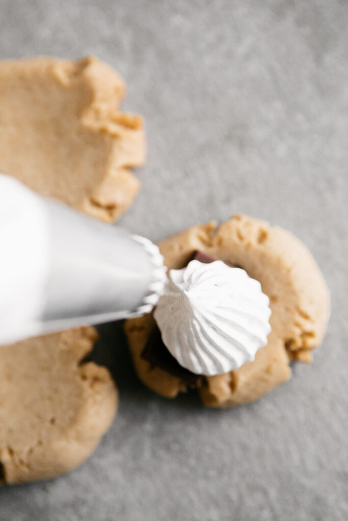 Piping marshmallow fluff onto a cookie 