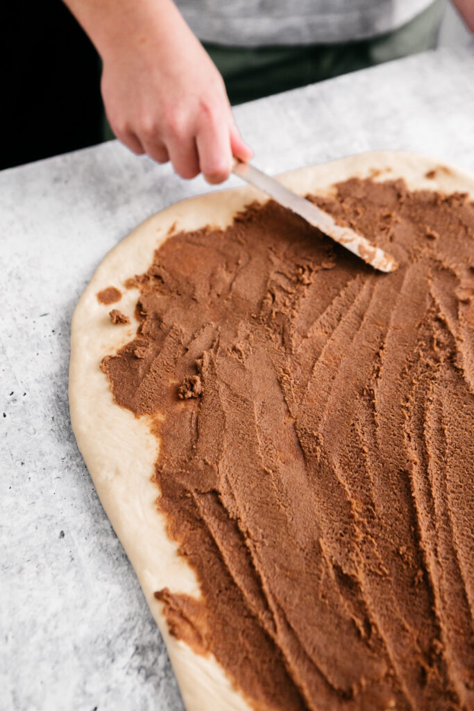 Spreading cinnamon and sugar on dough 