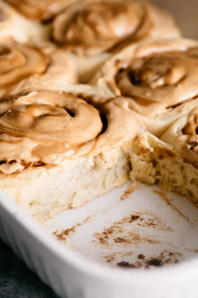 A dish of cinnamon rolls with one removed 