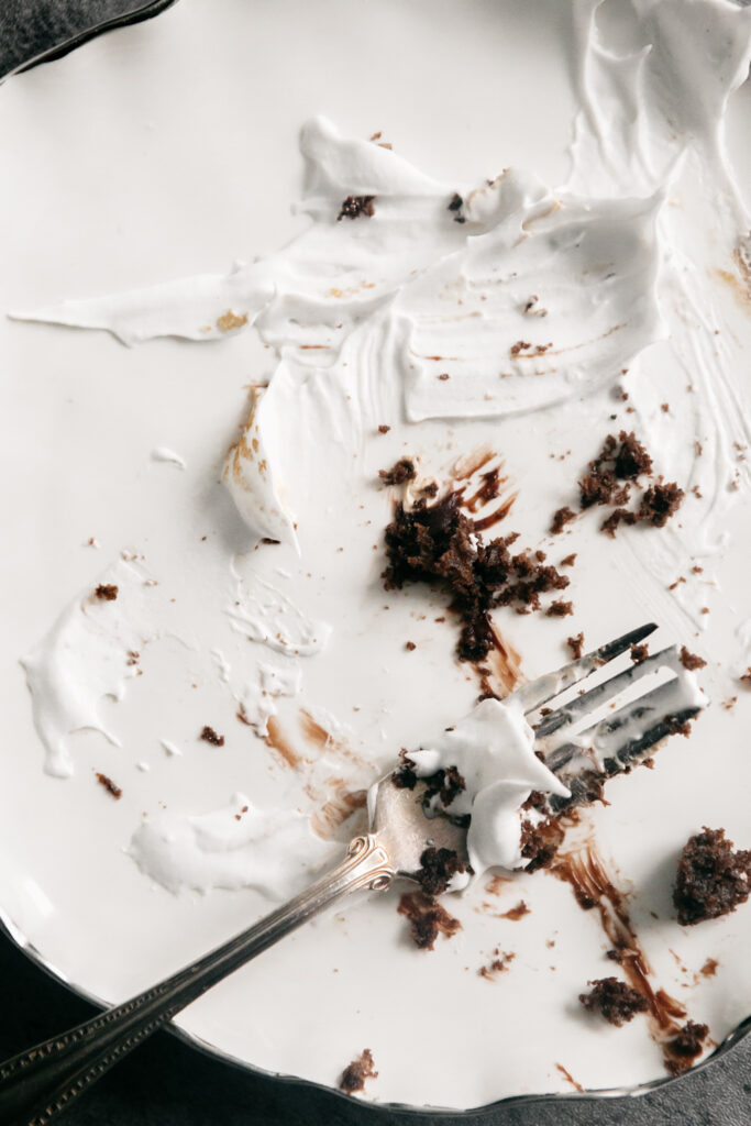 An empty white plate with chocolate cake crumbs 
