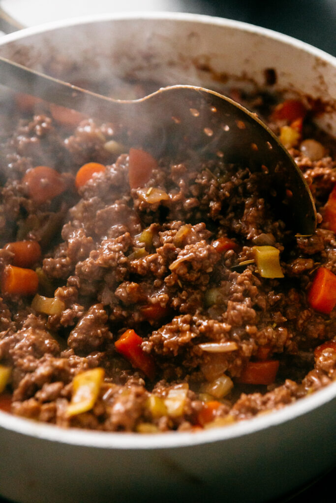 beef mixture being cooked in a pan 