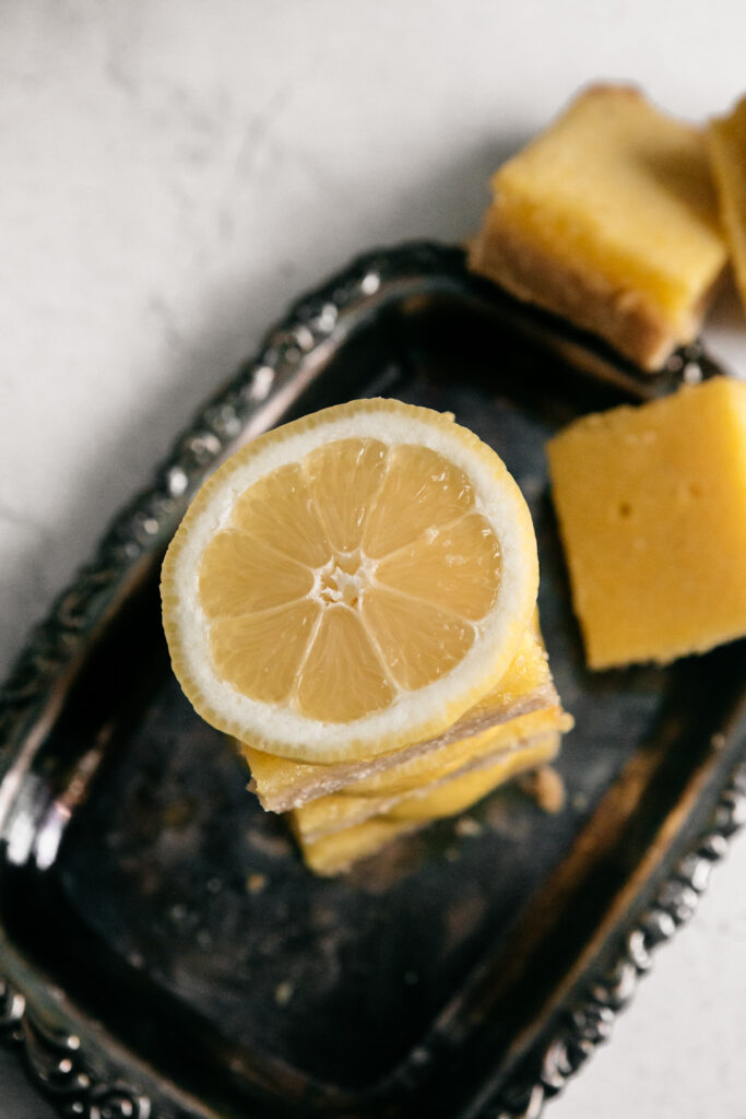 a lemon slice on top of a stack of dessert bars 