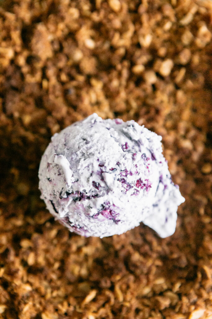 a scoop of blueberry ice cream on a cheesecake 