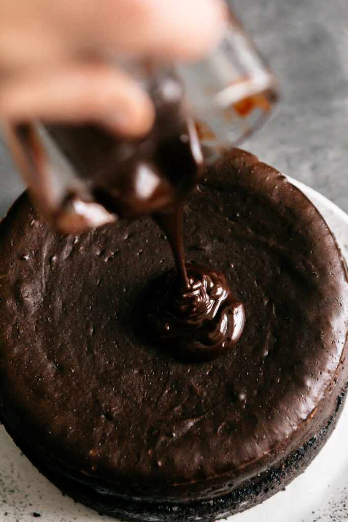 pouring ganache over a cheesecake 